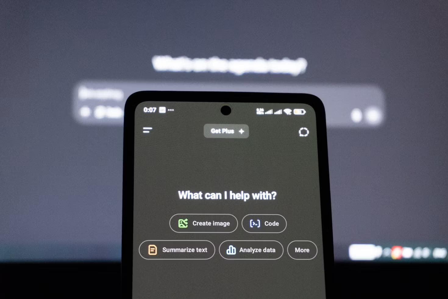 Hender holder en mobiltelefon med et chatbot-grensesnitt i mørket